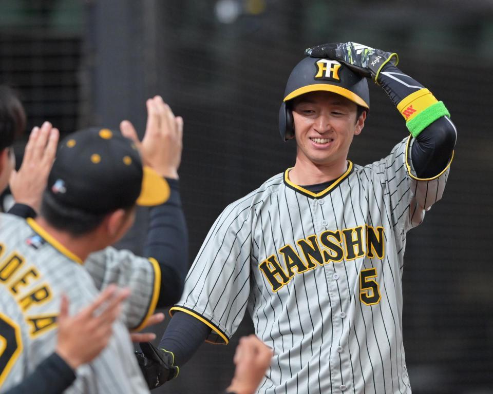 　１回、中野の適時三塁打で先制のホームを踏み、ナインの出迎えに笑顔を見せる近本（撮影・立川洋一郎）