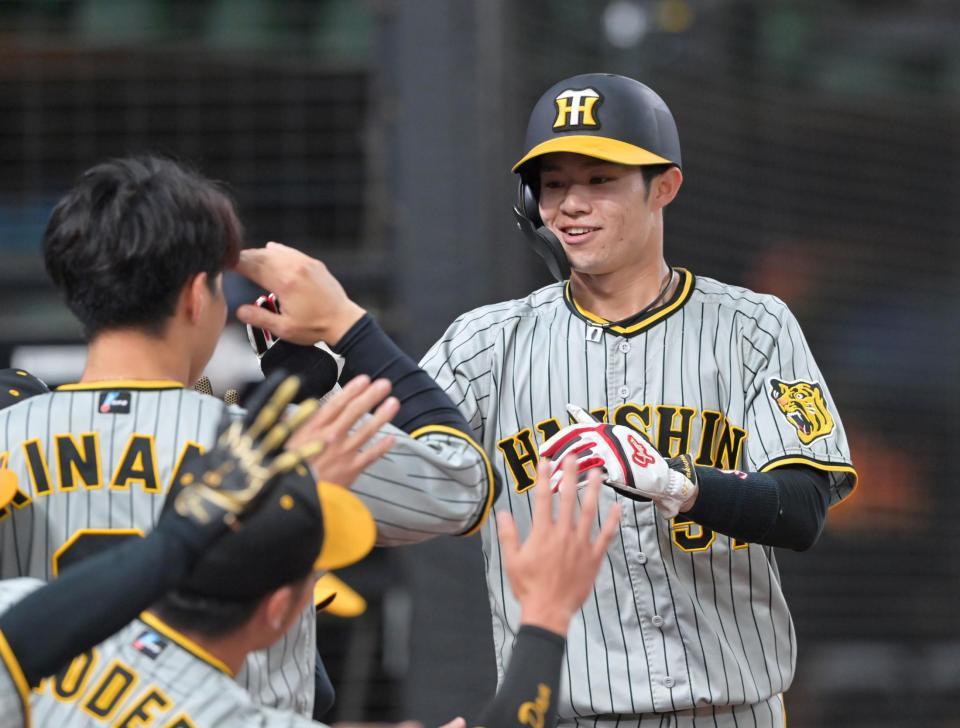 　１回、ノイジーの遊ゴロで生還し、ナインの出迎えに笑顔を見せる中野（撮影・立川洋一郎）