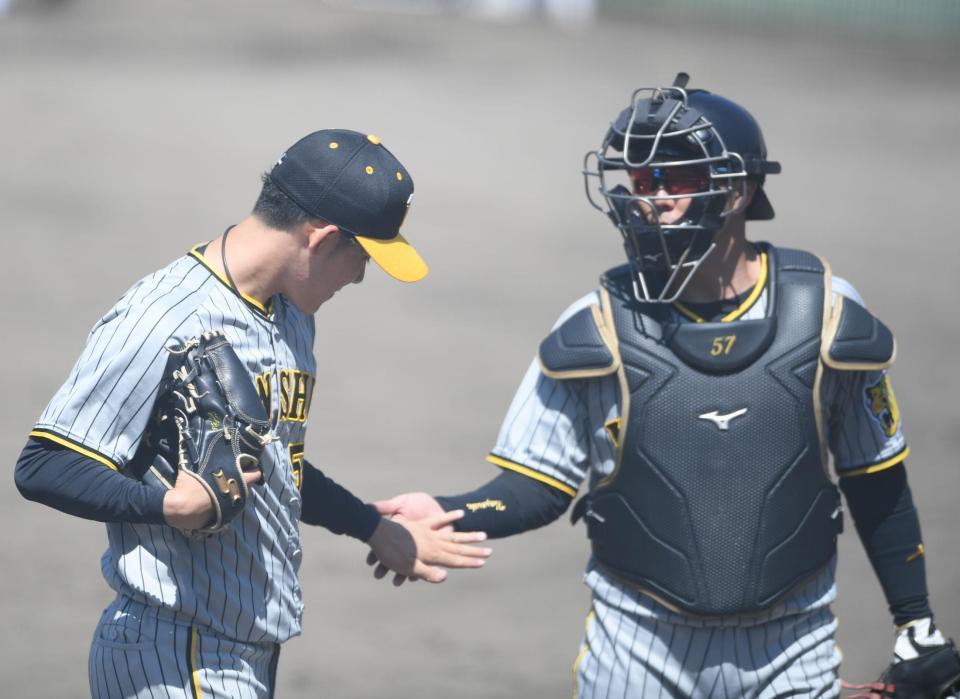 　４回、得点を許さず投げ終え長坂（右）とタッチをかわす富田（撮影・石井剣太郎）