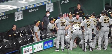 　円陣を組む阪神ナインと笑顔を見せる岡田監督（左）＝撮影・佐々木彰尚