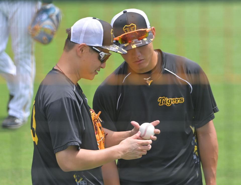 　西純（右）に変化球の握りをアドバイスする大竹（撮影・立川洋一郎）