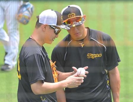 　西純（右）に変化球の握りをアドバイスする大竹