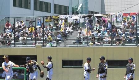 　故・横田慎太郎さんのユニフォームとタオルがスタンド上段フェンスに掛られる中、シートノックを行う阪神ナイン（撮影・北村雅宏）
