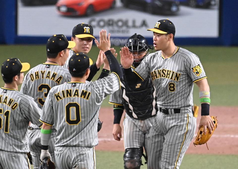 　勝利のハイタッチをかわす佐藤輝（右）ら阪神ナイン（撮影・飯室逸平）