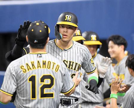 　７回、３ランを放ち、ナインとタッチを交わす佐藤輝