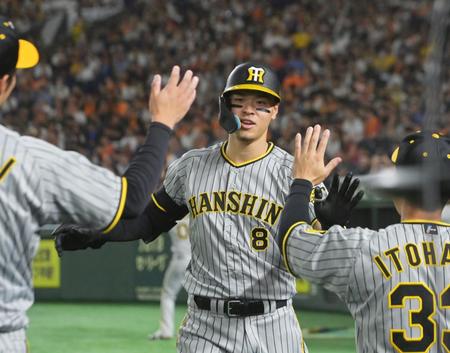 　２回、右翼スタンドへ先制ソロを放ち出迎えるナインとタッチを交わす佐藤輝（撮影・立川洋一郎）