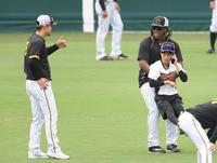 　佐藤輝（左）と話しながら電話中の通訳を抱えるミエセス（撮影・中田匡峻）