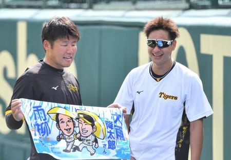 　青柳とのコラボタオルを手に取る藤本通訳（左）を見て、笑顔の大竹（撮影・中田匡峻）