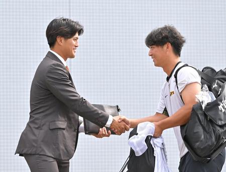 　戦力外通告を受けた板山（左）は井坪と握手を交わす（撮影・中田匡峻）