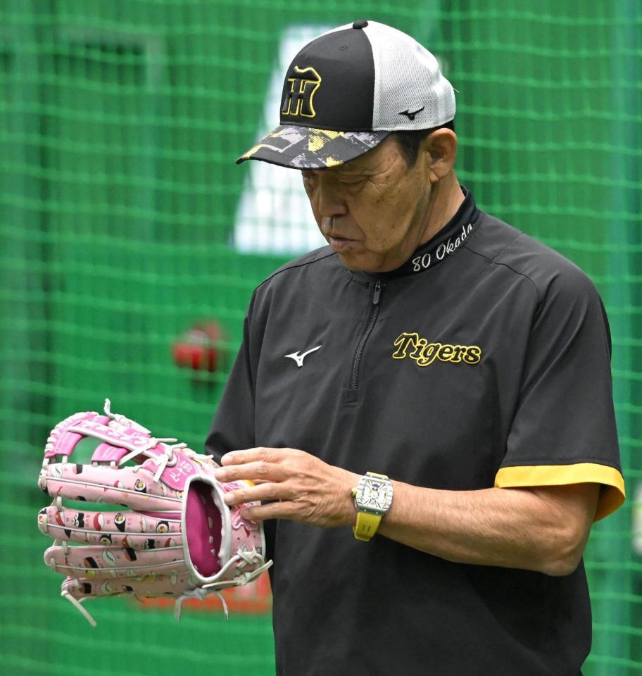 　「ピーヤ55」と記されたピンクのグラブを見つめる岡田監督（２０日撮影）
