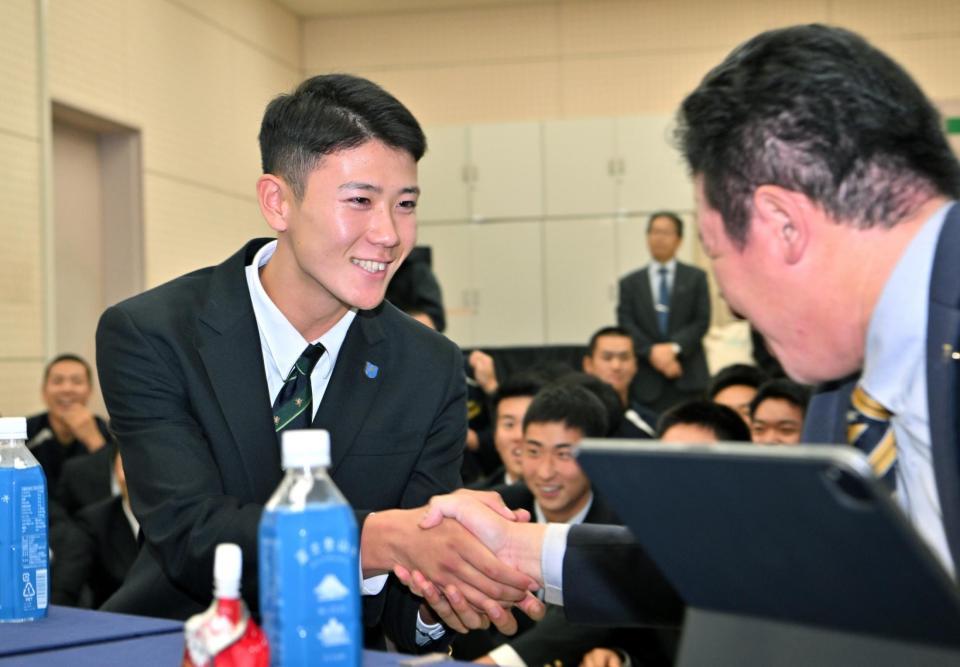 　阪神に３位で指名され、笑顔で須江監督（右）と握手する仙台育英・山田脩也