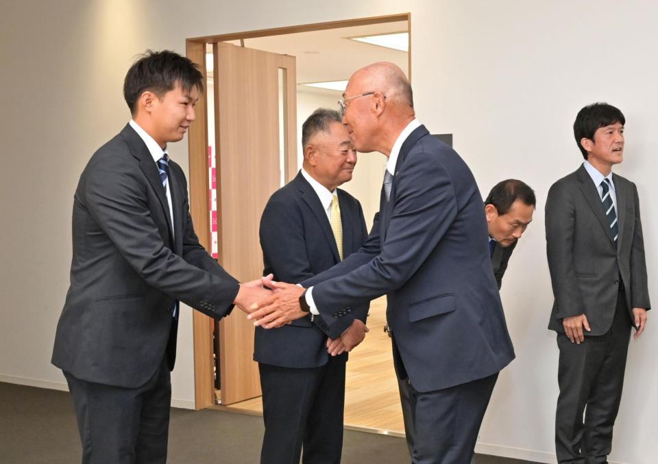 　阪神の指名あいさつを受け、畑山統括スカウト（手前右）と握手を交わすドラフト６位指名の大経大・津田淳哉（撮影・立川洋一郎）