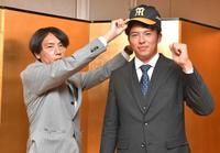 　仮契約を終え、渡辺コーチ（左）から帽子をかぶせてもらう