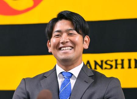 　契約更改を終えて会見に臨み笑顔を見せる岡留（撮影・立川洋一郎）