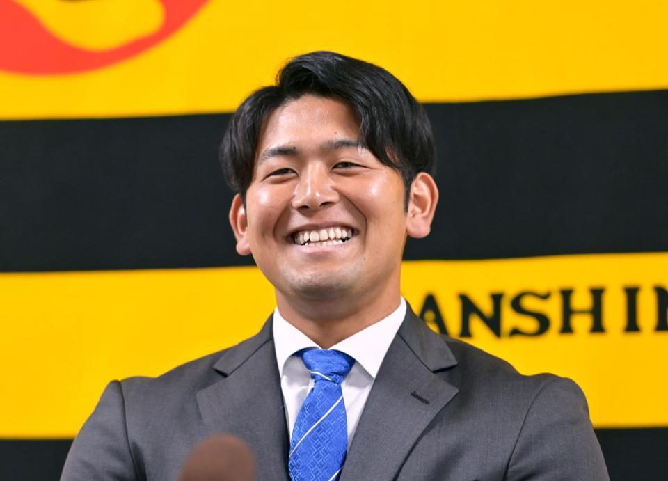 　契約更改を終えて会見に臨み笑顔を見せる岡留（撮影・立川洋一郎）