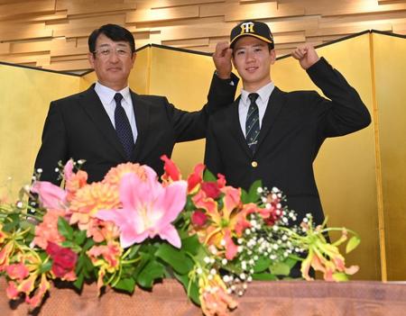 　葛西稔スカウト（左）に帽子をかぶせてもらう阪神３位指名の山田（撮影・西岡正）