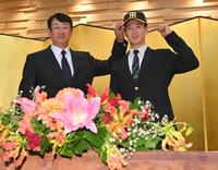 　葛西稔スカウト（左）に帽子をかぶせてもらう阪神３位指名の山田（撮影・西岡正）