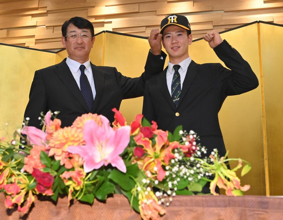 　葛西稔スカウト（左）に帽子をかぶせてもらう阪神３位指名の山田（撮影・西岡正）