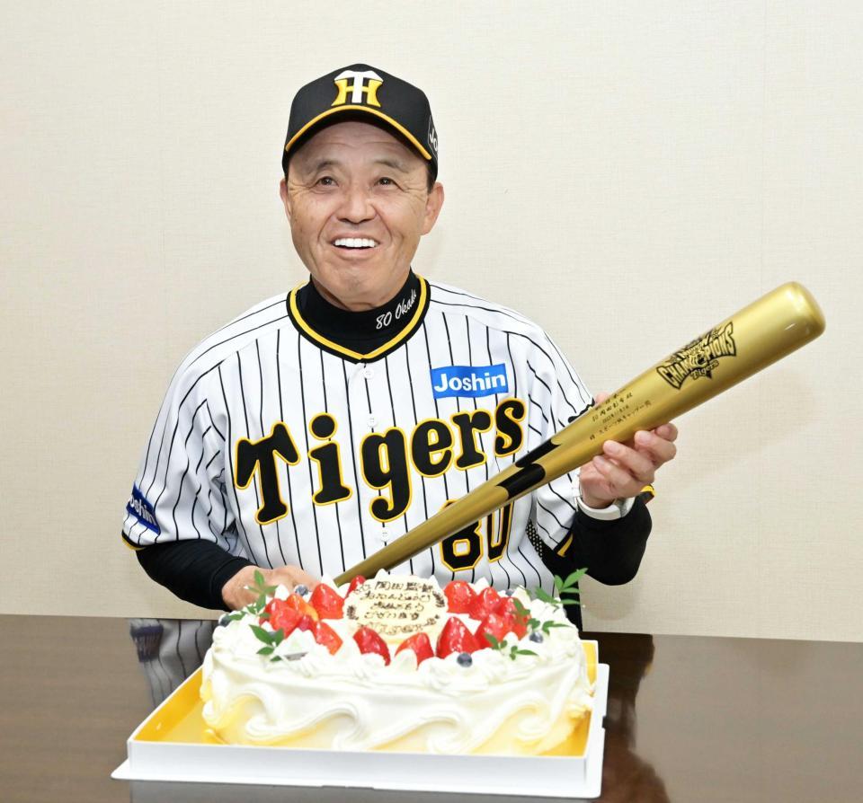 　バースデーケーキの前でプレゼントされたバットを手に笑顔を見せる岡田監督