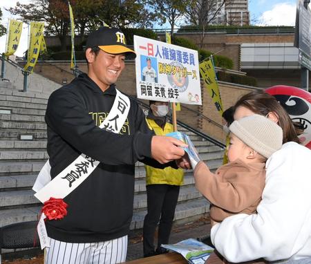 　「一日人権擁護委員」に任命され、ファンの赤ちゃんに啓発物品のセットを手渡す岡留（撮影・高部洋祐）