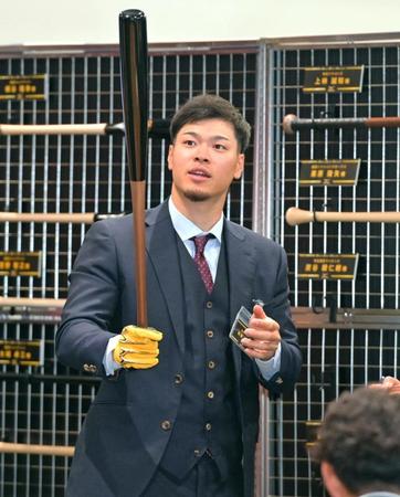 　バットを手にして感触を確かめる佐藤輝（撮影・立川洋一郎）