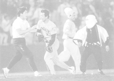 　試合終了後ファンがグラウンドに乱入、帽子を奪い返す松永（左から２人目）＝１９９３年５月２９日