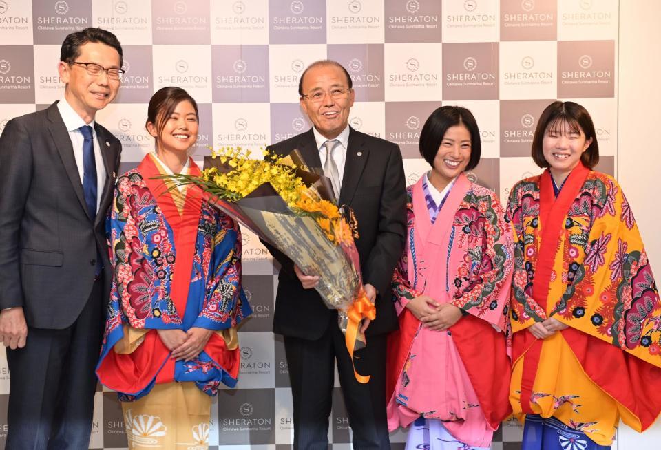 　宿舎に到着して歓迎の花束を受け取り笑顔を見せる岡田監督（中央）＝撮影・立川洋一郎