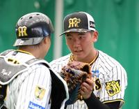 　ブルペンで投げ終えた門別（右）は梅野とタッチを交わす（撮影・中田匡峻）