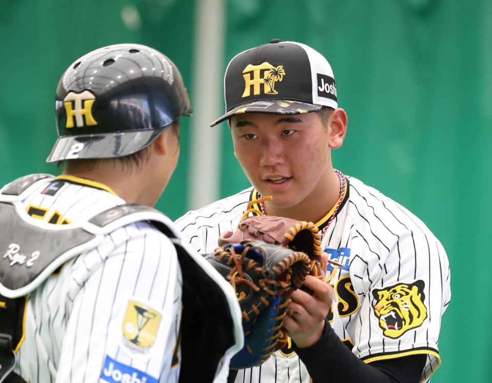 　ブルペンで投げ終えた門別（右）は梅野とタッチを交わす（撮影・中田匡峻）