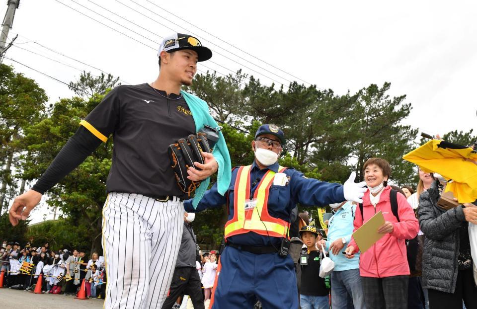 　特守を終えた佐藤輝（左）は多くの歓声を受け、ガードマンに守られながら引き揚げる（撮影・中田匡峻）