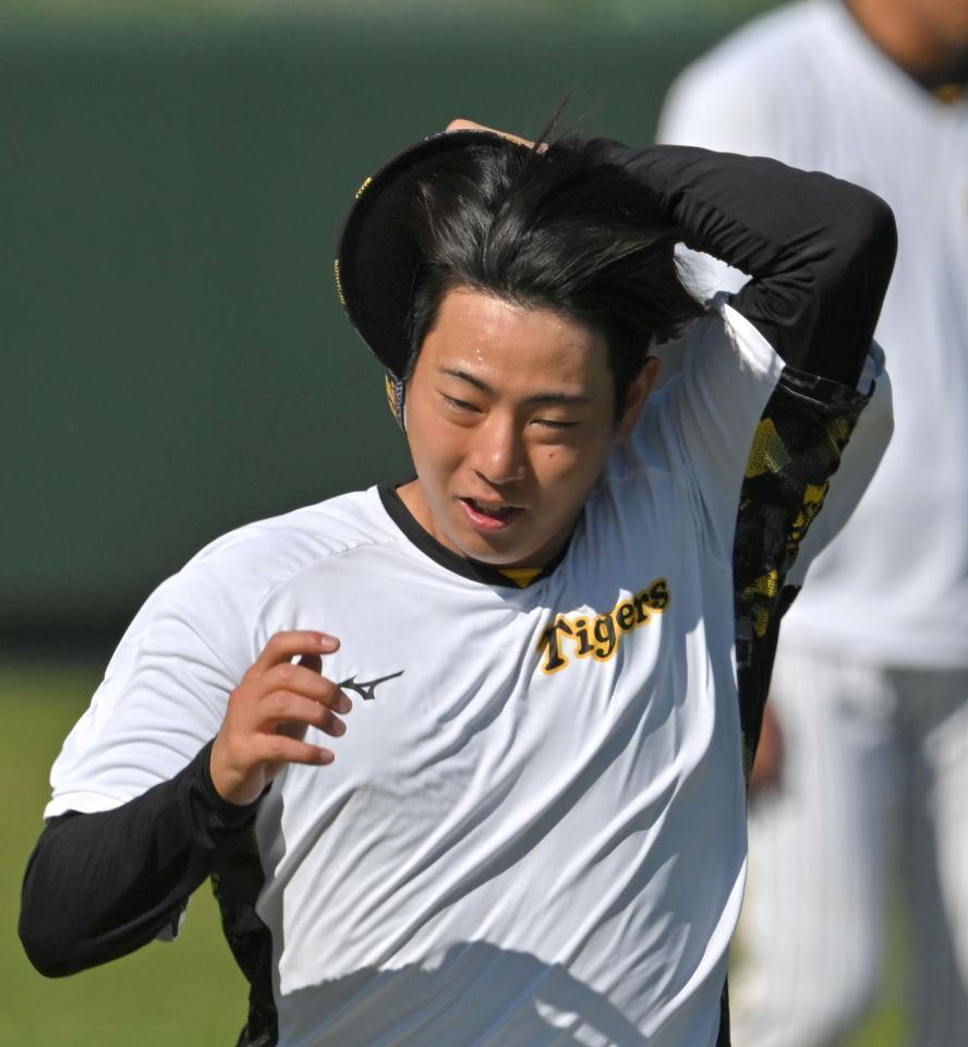 　ウオーミングアップ中、風に飛ばされる帽子を押さえる下村（撮影・北村雅宏）