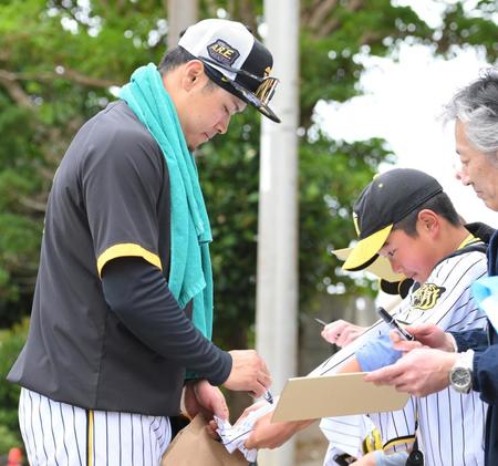 　居残り特守を終え、ファンの男の子が差し出したユニホームにサインをする佐藤輝（撮影・伊藤笙子）