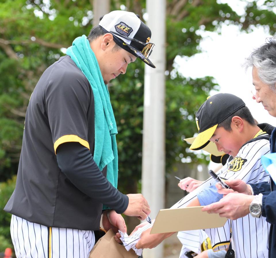 　居残り特守を終え、ファンの男の子が差し出したユニホームにサインをする佐藤輝（撮影・伊藤笙子）