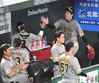 　４回のピンチを切り抜け、梅野（左）とタッチを交わす才木（撮影・棚橋慶太）