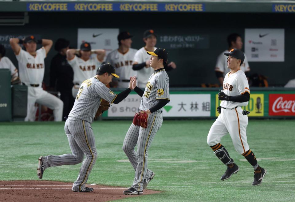 　６回、梶谷（右）を一ゴロに打ち取り、大山（左）とタッチを交わす才木（撮影・中田匡峻）