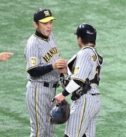 　梅野（右）からウイニングボールを受け取る岡田監督（撮影・棚橋慶太）