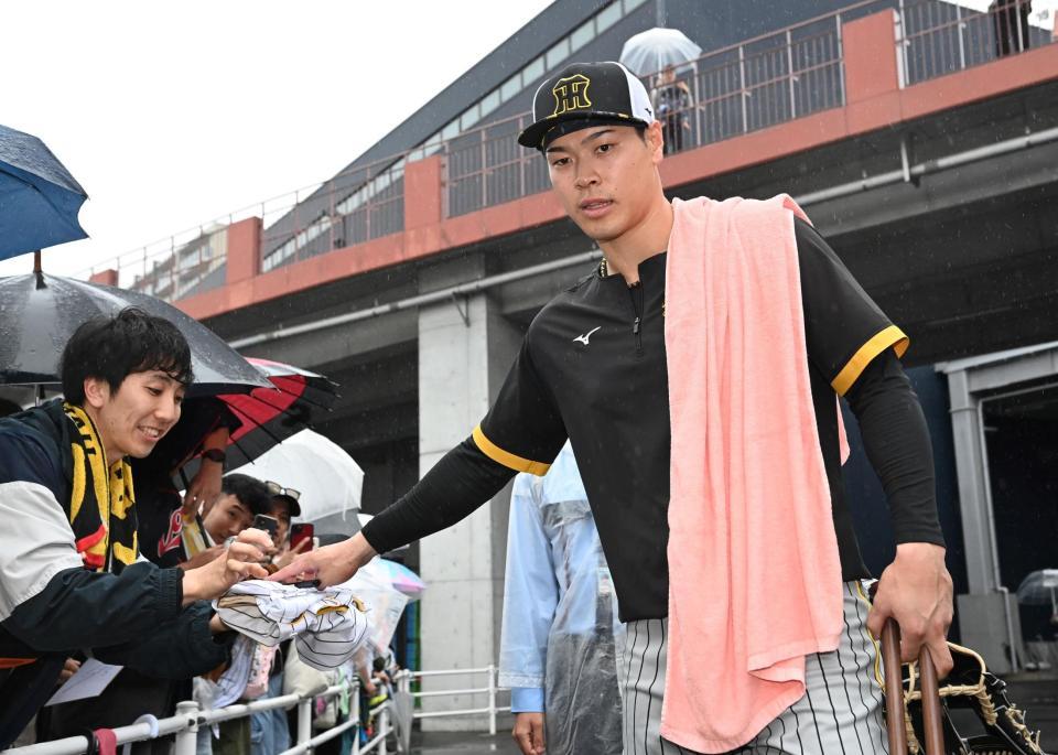 　練習を終えて引き揚げる際、ファンにサインする佐藤輝（撮影・田中太一）