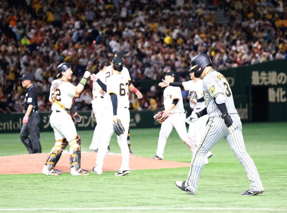 　９回、二飛に倒れ、喜ぶ巨人ナインの横を引き揚げる大山（右）＝撮影・西岡正