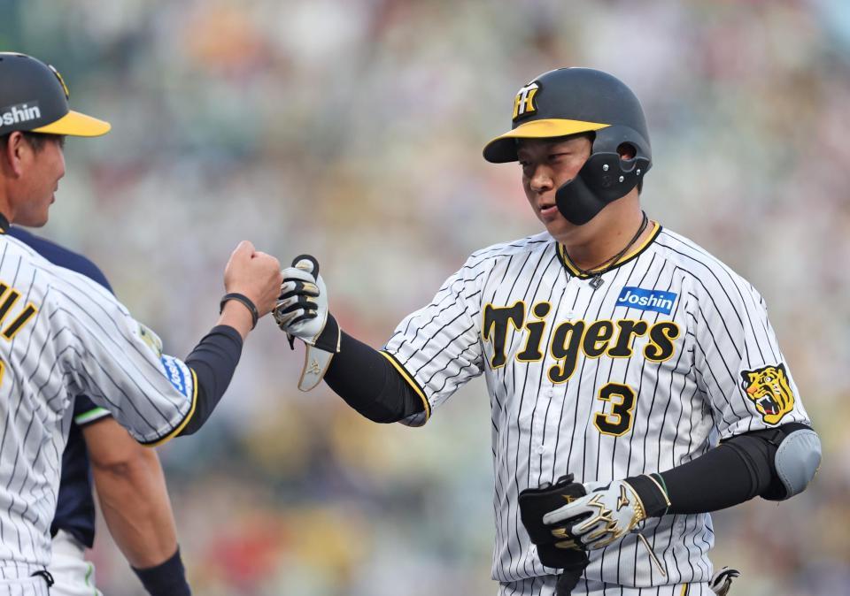 ２回阪神無死、左前打を放ち、阪神・筒井壮外野守備走塁コーチ（左）とタッチを交わす阪神・大山悠輔＝甲子園（撮影・中田匡峻）