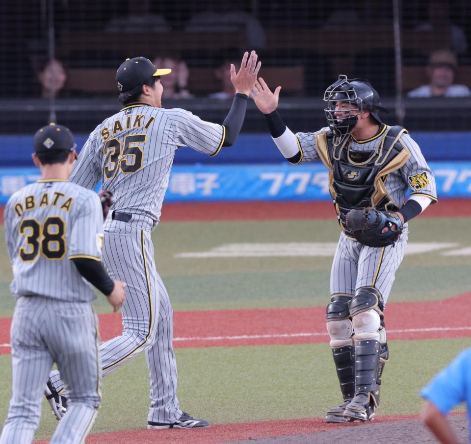 　完封勝利した才木（左）とタッチを交わす梅野（撮影・西岡正）