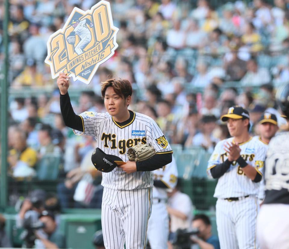 　２０００投球回を達成し記念ボードを掲げる西（撮影・立川洋一郎）