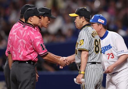 　ピンク色のシャツ姿の審判と握手をする岡田監督（撮影・田中太一）