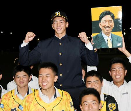 　阪神から２位指名され、藤川監督の写真の隣で笑顔でガッツポーズをする徳学園・今朝丸裕喜（撮影・田中太一）