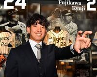 　藤川監督のユニホームが飾られる前でポーズを決める伊原（撮影・中田匡峻）