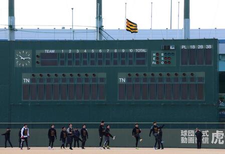 　半旗が掲げられる中、アップをする阪神の新人選手たち（撮影・中田匡峻）