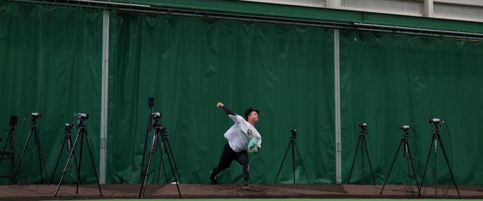 　マーカレス・モーションキャプチャーが設置される中、投球練習をする村上（撮影・中田匡峻）