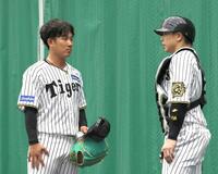 　ブルペンで梅野（右）と話す伊原