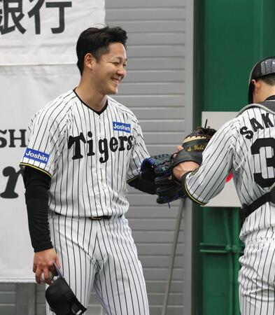 　ブルペンでの投球練習を終え、栄枝とグラブタッチを交わす木下（左）＝撮影・北村雅宏