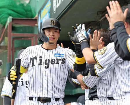 　１回、ライトに先制２ランを放ち、ナインとタッチを交わす佐藤輝（撮影・中田匡峻）