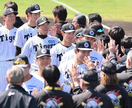 　具志川キャンプを打ち上げ、スタッフらと笑顔でタッチする平田２軍監督（左から３人目）＝撮影・西田忠信